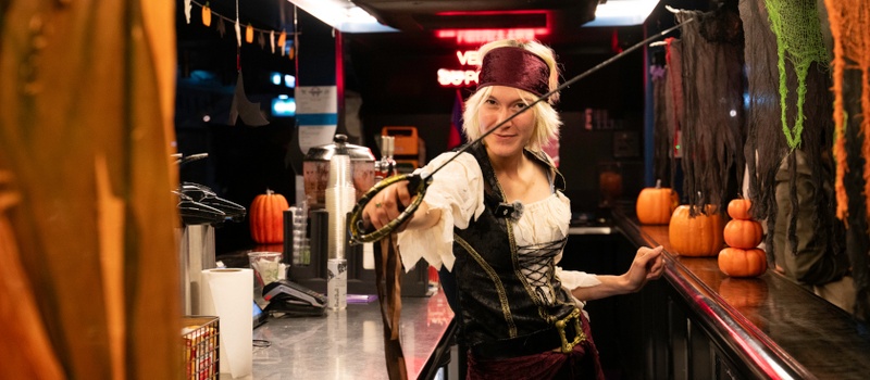 Femme en costume de pirate brandissant une épée au bar du bateau décoré pour Halloween