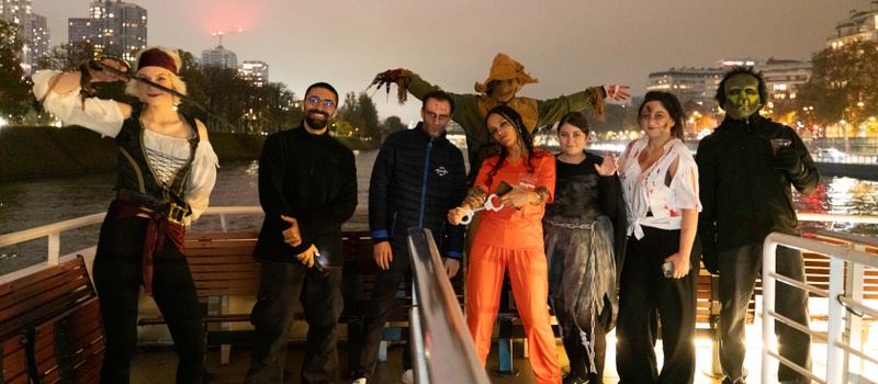 Groupe en costumes d’Halloween sur le pont du bateau, avec Paris illuminé en arrière-plan
