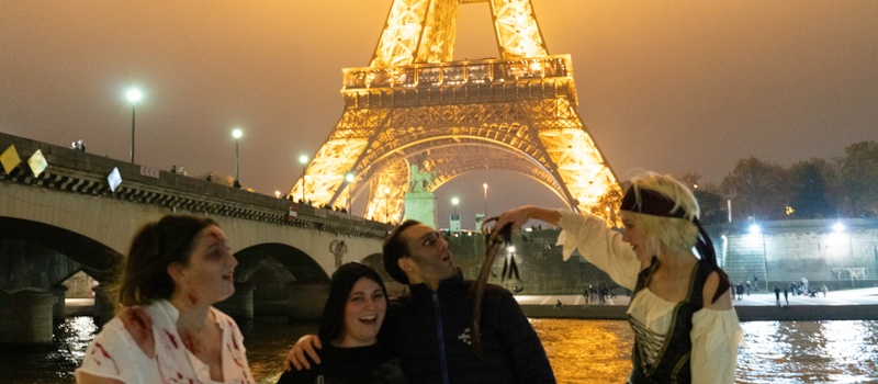 Groupe à bord du bateau devant la tour Eiffel illuminée, avec une femme en costume de pirate